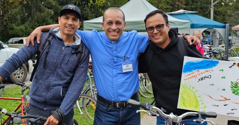 Father Enrique Martinez poses with two migrant farm workers and their newly received bicycles at the diocese of Huron's 2023 migrant worker appreciation day.